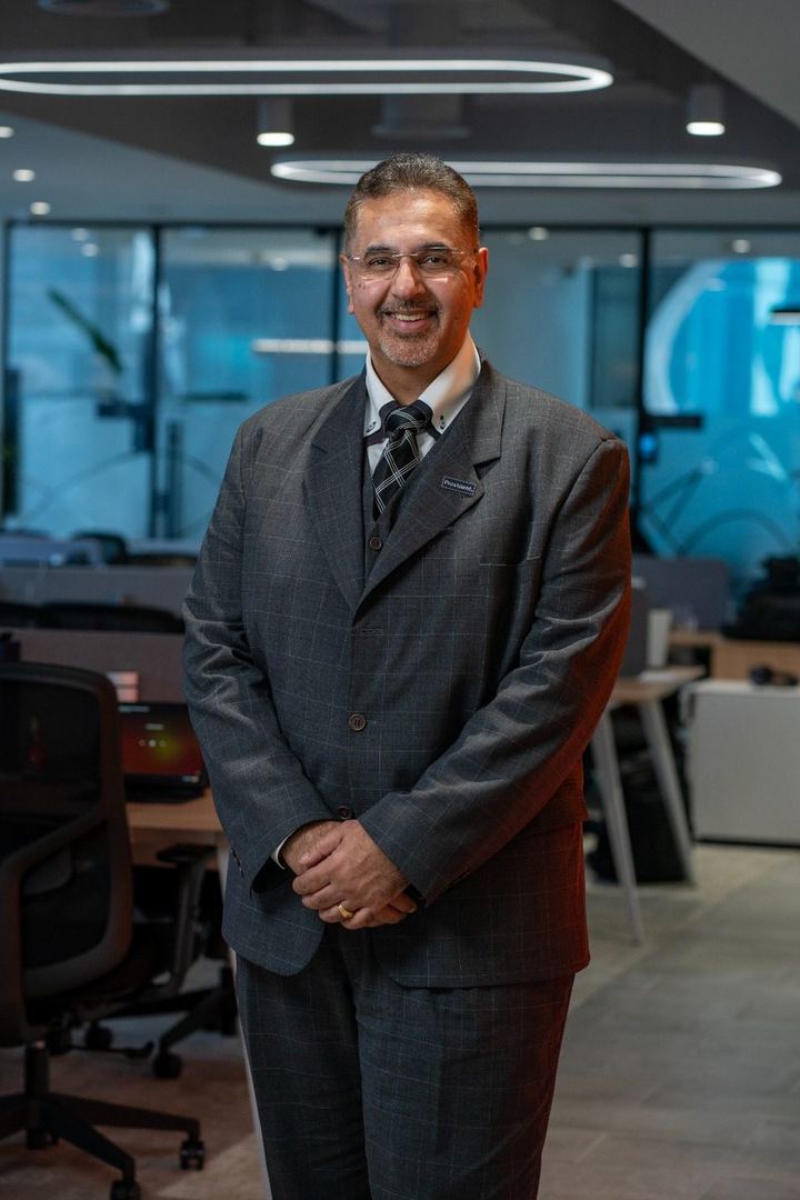 Dr Deepak Songra, full length in a grey suit, at the Provident Real Estate office in Business Bay